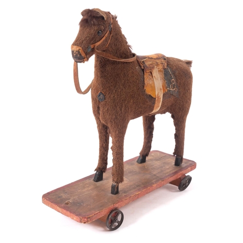 651 - A late 19th/ early 20th century pull along horse, the brown fabric horse with boot button eyes,  app... 