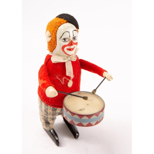 654 - A Schuco tinplate clockwork Drumming Clown, black felt beret over ginger hair and painted tinplate f... 