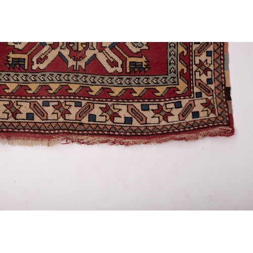 1064 - A Kurdish rug, the brick red field with ivory and pastel geometric medallions, enclosed by a main iv... 