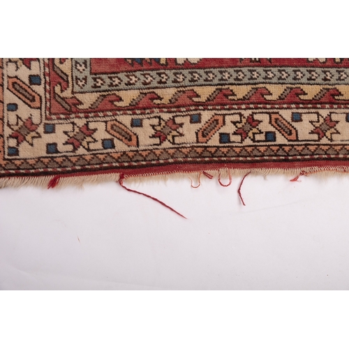 1064 - A Kurdish rug, the brick red field with ivory and pastel geometric medallions, enclosed by a main iv... 