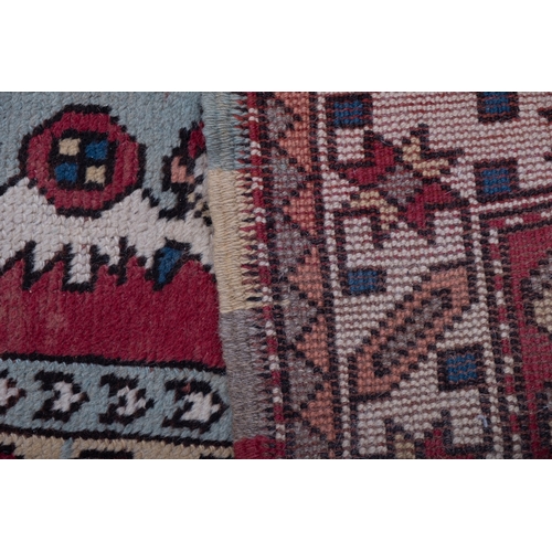 1064 - A Kurdish rug, the brick red field with ivory and pastel geometric medallions, enclosed by a main iv... 