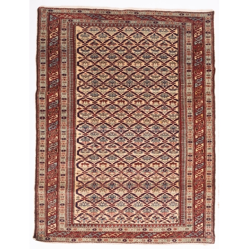 1065 - An Indo Persian rug, the ivory lattice field with geometric motifs, enclosed by a main wine hooked d... 