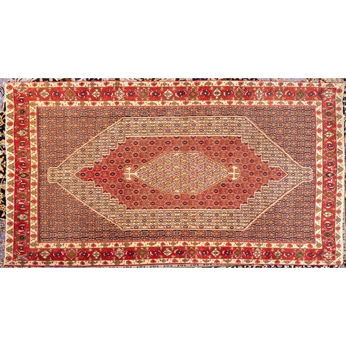 1074 - A Senneh carpet, the geometric design field with hexagonal beige and red stepped pole medallions, ha... 