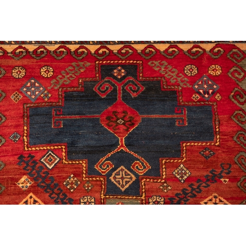 1079 - A Kasak rug, the wine field with triple indigo and pastel blue stepped cruciform medallions, surroun... 