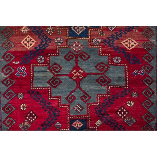 1079 - A Kasak rug, the wine field with triple indigo and pastel blue stepped cruciform medallions, surroun... 