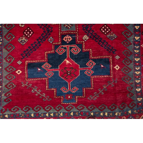 1079 - A Kasak rug, the wine field with triple indigo and pastel blue stepped cruciform medallions, surroun... 