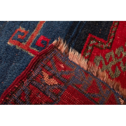 1079 - A Kasak rug, the wine field with triple indigo and pastel blue stepped cruciform medallions, surroun... 