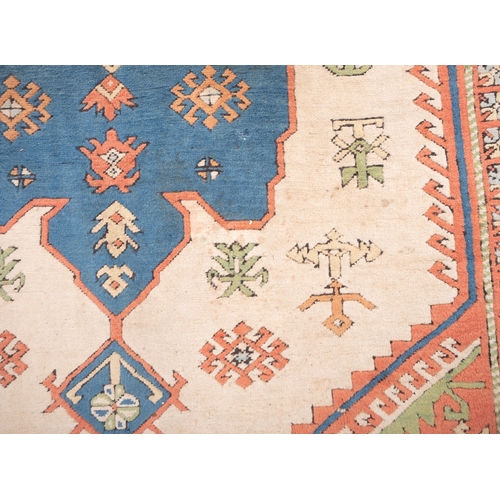 1082 - A Turkish carpet, the camel field with a central pastel blue geometric pole medallion with lozenge c... 