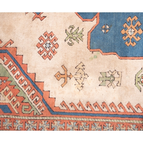 1082 - A Turkish carpet, the camel field with a central pastel blue geometric pole medallion with lozenge c... 