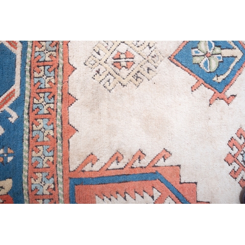 1082 - A Turkish carpet, the camel field with a central pastel blue geometric pole medallion with lozenge c... 