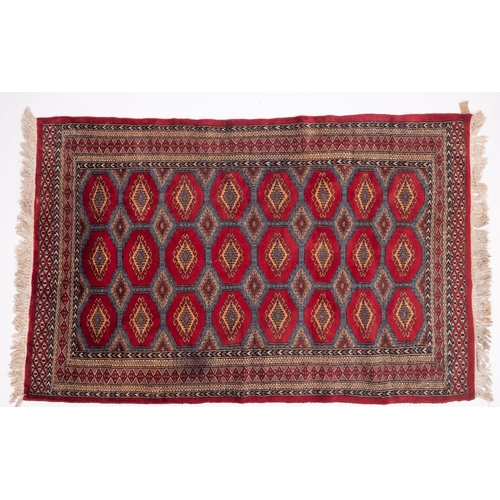 1086 - A Pakistan rug of Turkoman design, the red octagonal panelled field with repeated hooked lozenge med... 