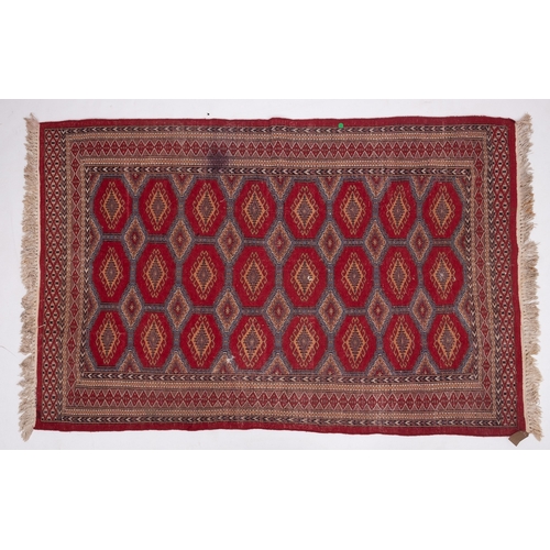 1086 - A Pakistan rug of Turkoman design, the red octagonal panelled field with repeated hooked lozenge med... 