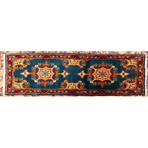 1090 - A Sarouk runner, the green field with twin ivory scrolling cartouche pointed medallions with floral ... 