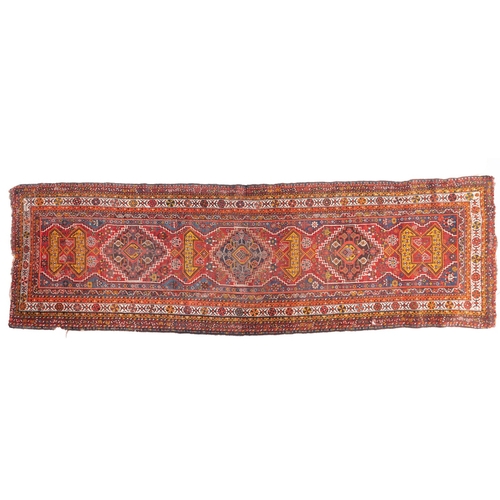 1091 - A South Persian runner, the red field with indigo hooked and stepped and geometric medallions, all o... 