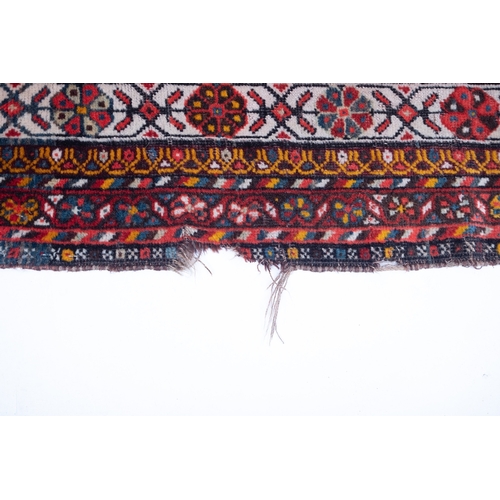 1091 - A South Persian runner, the red field with indigo hooked and stepped and geometric medallions, all o... 