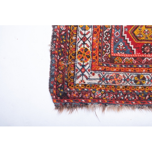 1091 - A South Persian runner, the red field with indigo hooked and stepped and geometric medallions, all o... 