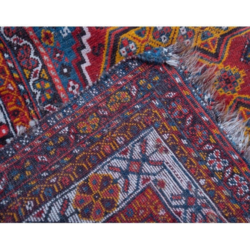 1091 - A South Persian runner, the red field with indigo hooked and stepped and geometric medallions, all o... 