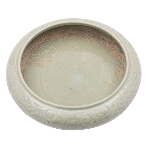 45 - A Chinese celadon bowl of compressed form, decorated in relief with dragons amongst scrolling tendri... 