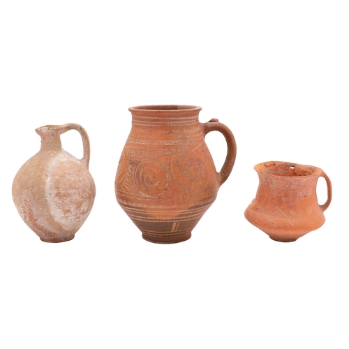 62 - A Greek terracotta jug painted with scrolling motifs between line borders, 20cm; a similar cup, 11cm... 