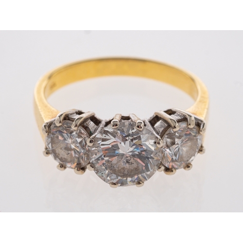 554 - An 18ct gold diamond three stone ring, the central brilliant cut diamond, estimated to weigh 1.90 ca... 