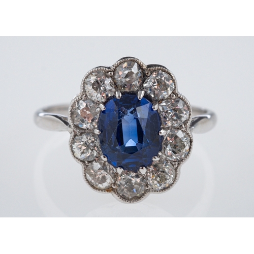 559 - A sapphire & diamond ring, the oval faceted sapphire of  around 1.75 carats, within a border of old ... 