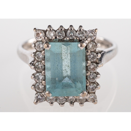 588 - An aquamarine and diamond ring, the rectangular cut aquamarine claw set within a surround of brillia... 