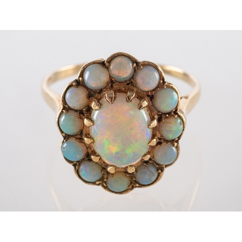 594 - An opal ring, the central oval cabochon opal claw set within a surround of circular cabochon opals, ... 