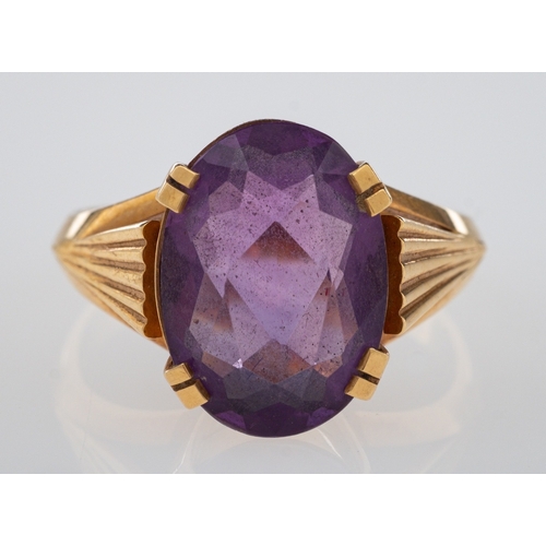 616 - A dress ring set with an oval faceted amethyst, the shoulders cut with fan form grooves, marked 750 ... 