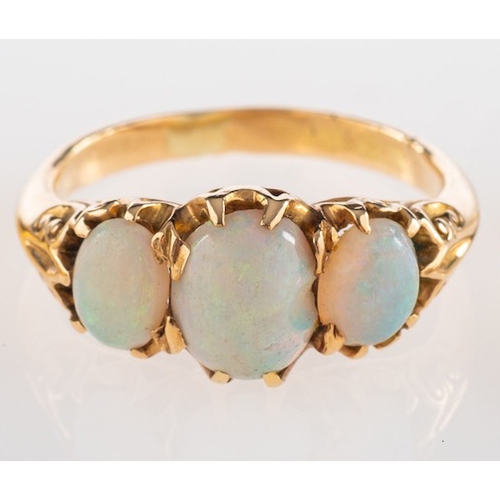 595 - A three stone opal ring, set with three oval cabochon opals in claw settings, ring size O 1/2.