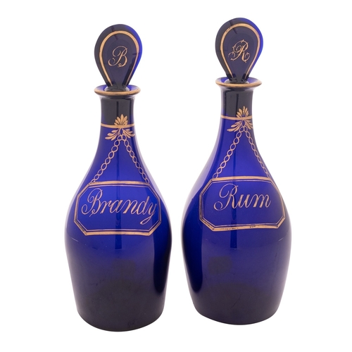 11 - A pair of Bristol blue glass 'Rum' and 'Brandy' decanters and stoppers the baluster bodies with gilt... 