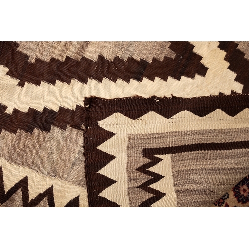 1255 - A Navajo flatweave, the beige field with a central chocolate brown and ivory lozenge medallion, encl... 