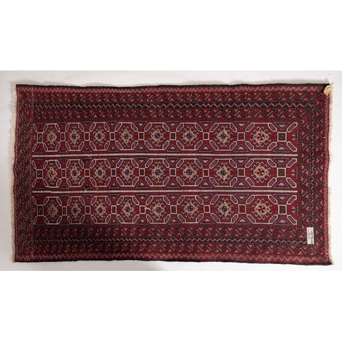 1263 - An Afghan Balouch rug, the red striped field with three rows of hooked lozenge medallions, enclosed ... 