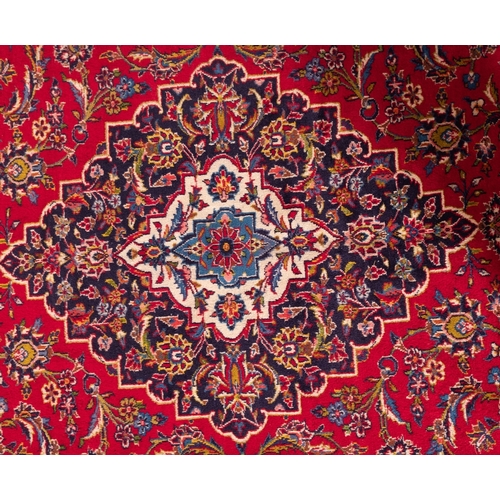 1288 - A Kashan carpet, the madder cartouche field with a central indigo shaped lozenge pole medallion, all... 