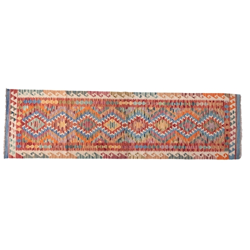 1293 - An Anatolian Turkish Kilim, the bright multi coloured field with a row of serrated lozenge medallion... 