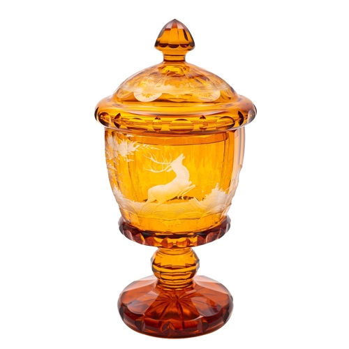 17 - A Bohemian amber flashed goblet and cover, intaglio decorated with a stag and doe in a wooded landsc... 