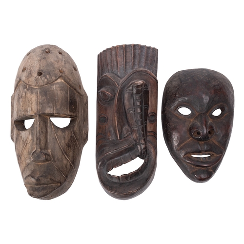 418 - Three carved wood tribal masks, 20th century; including one with a cobra rising from the open mouth,... 