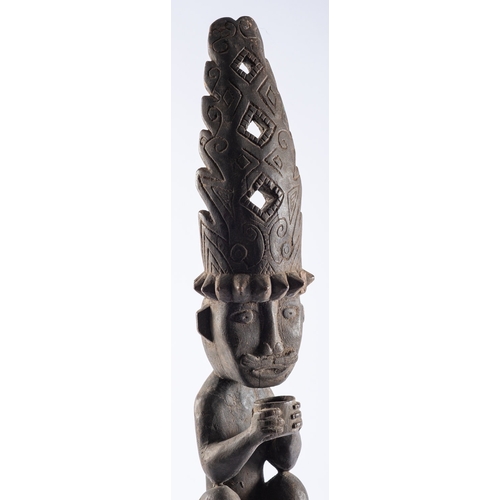 431 - An Indonesian carved wooden ancestor figure of Adu Zatua, the naked figure with elaborate head dress... 