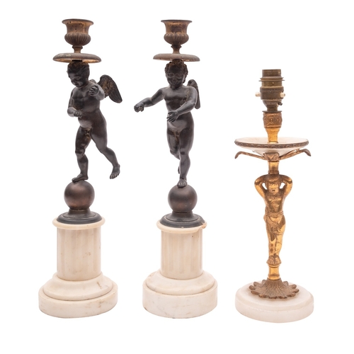 448 - A pair of patinated bronze and marble mounted figural candlesticks, early 20th century; the urn sock... 