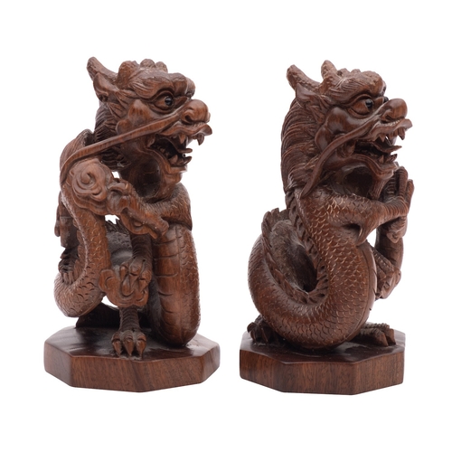 504 - A pair of Chinese hardwood 'dragon' carvings with ebony eyes, on octagonal bases, signed on mother o... 