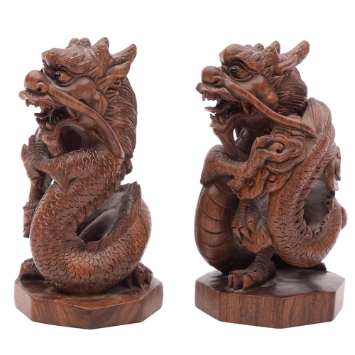 504 - A pair of Chinese hardwood 'dragon' carvings with ebony eyes, on octagonal bases, signed on mother o... 