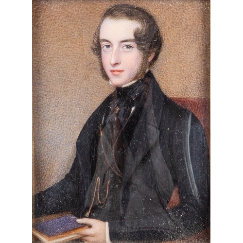 662 - British School, 19th Century A portrait miniature of a young man in black, seated and holding a book... 