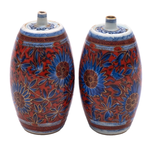 72 - A pair of Chinese porcelain spirit bottles, of barrel shaped form with blue painted and later clobbe... 