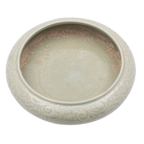 74 - A Chinese celadon bowl of compressed form, decorated in relief with dragons amongst scrolling tendri... 