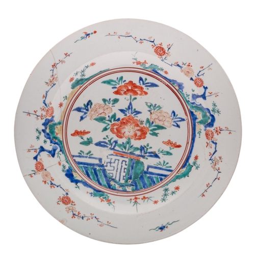 77 - A large Japanese Kakiemon-style charger painted in bright enamels with rockwork, a fence, peony and ... 