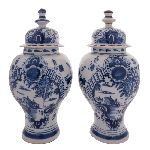 93 - A pair of Dutch Delft blue and white baluster vases and covers each painted with buildings by a rive... 