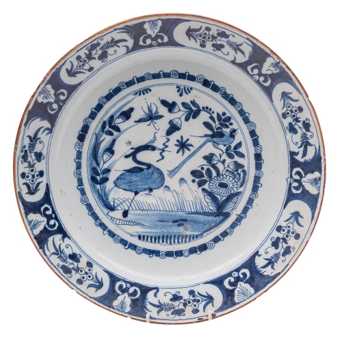 97 - A Bristol delft charger, painted in blue with birds and an insect amongst flowers and foliage within... 