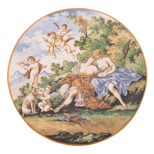 98 - An Italian maiolica plaque, in the Castelli manner painted with a courting couple surrounded by cupi... 