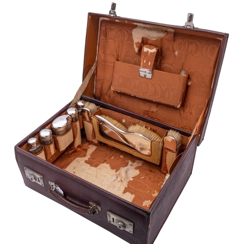 322 - A George V leather vanity case with silver and glass bottles, silver tops by W.A.I, London 1920, the... 