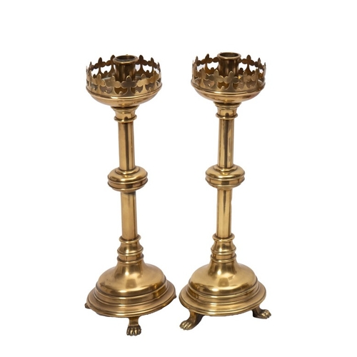 308 - A pair of Victorian brass 'Gothic' candlesticks with pierced sconces, turned stems and circular base... 