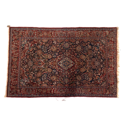 1110 - A Kashan rug, the indigo cartouche field with a central red, ivory and pastel blue lozenge pole meda... 